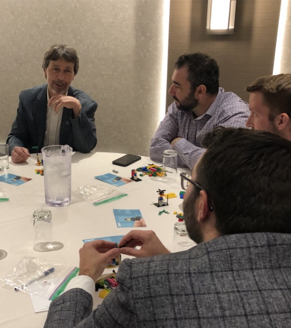 A participant explains to his teammates the meaning of his Lego creation.